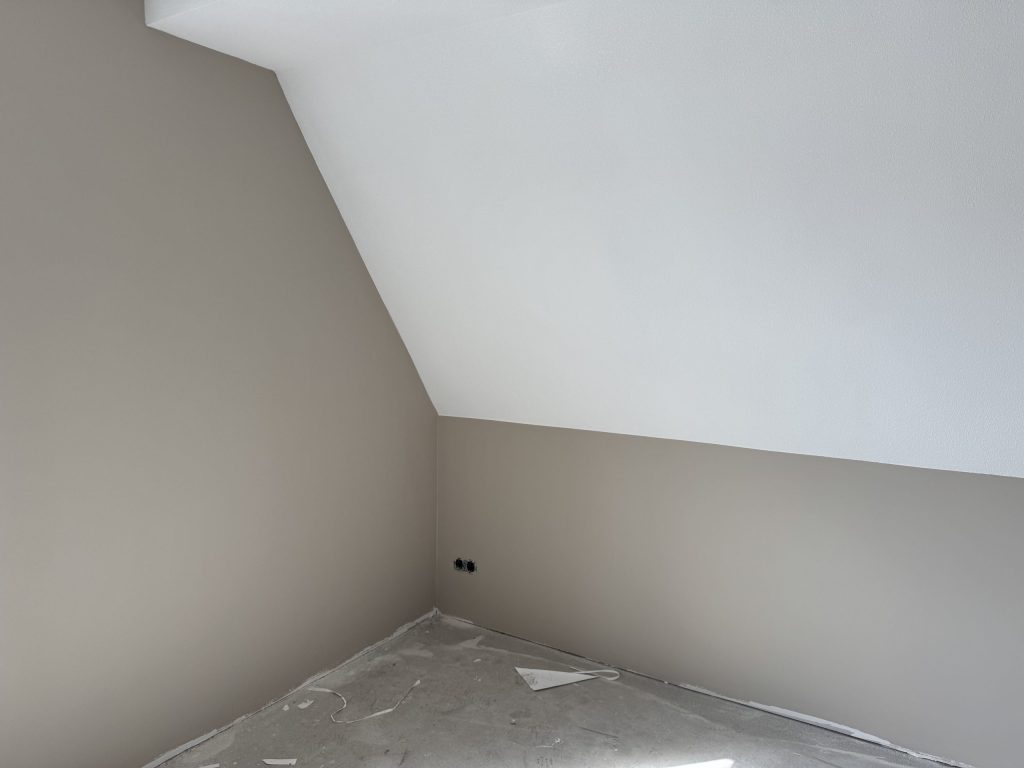 Zolderkamer in een nieuwbouwwoning met een schuine wand en een strak wit plafond